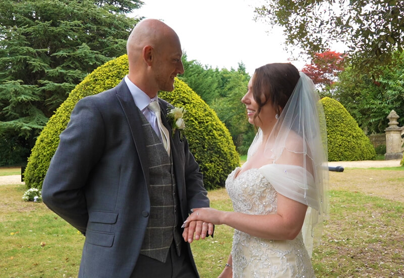 white couple looking at each other in garden just got married 