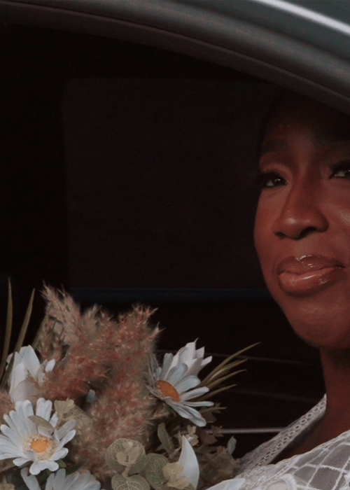 black bride sat in car with flowers 